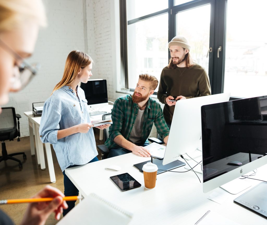 Image of young concentrated colleagues in office using computer. Looking aside.